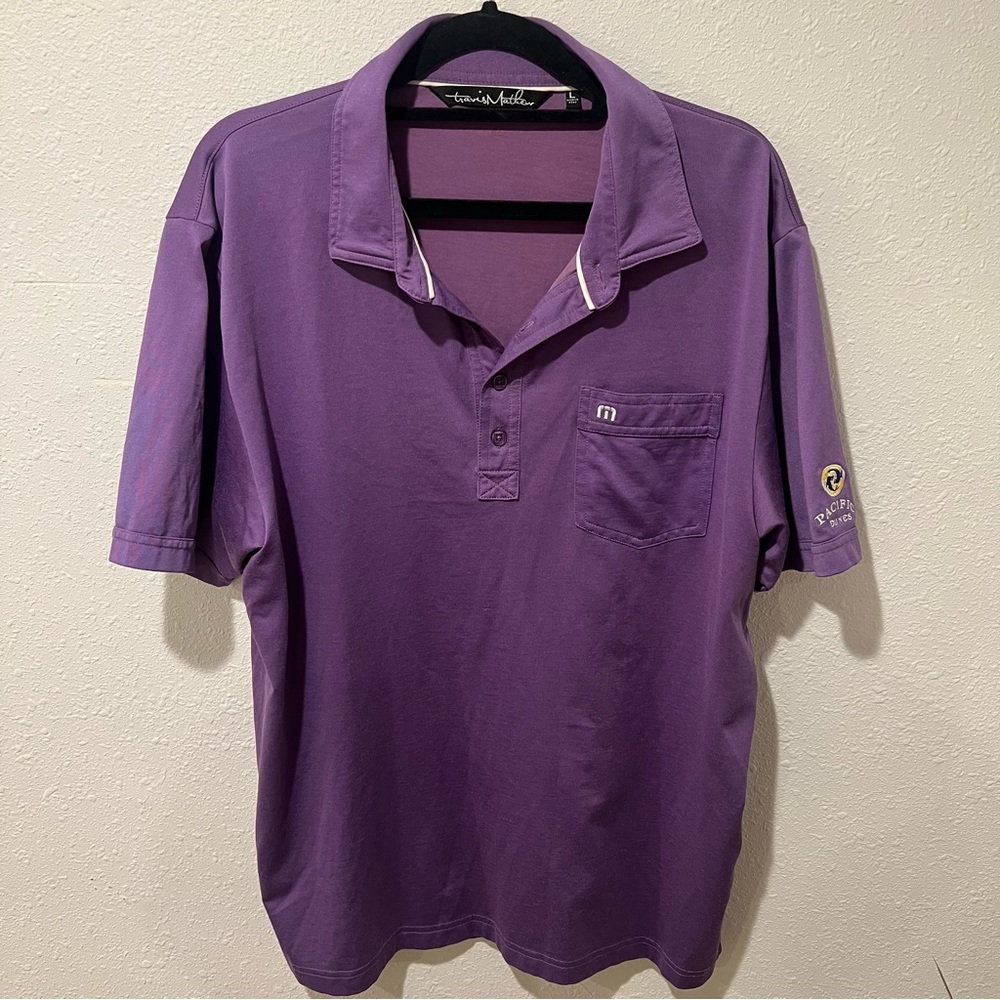 Travis Mathew’s purple golf shirt  with logo on sleeve
